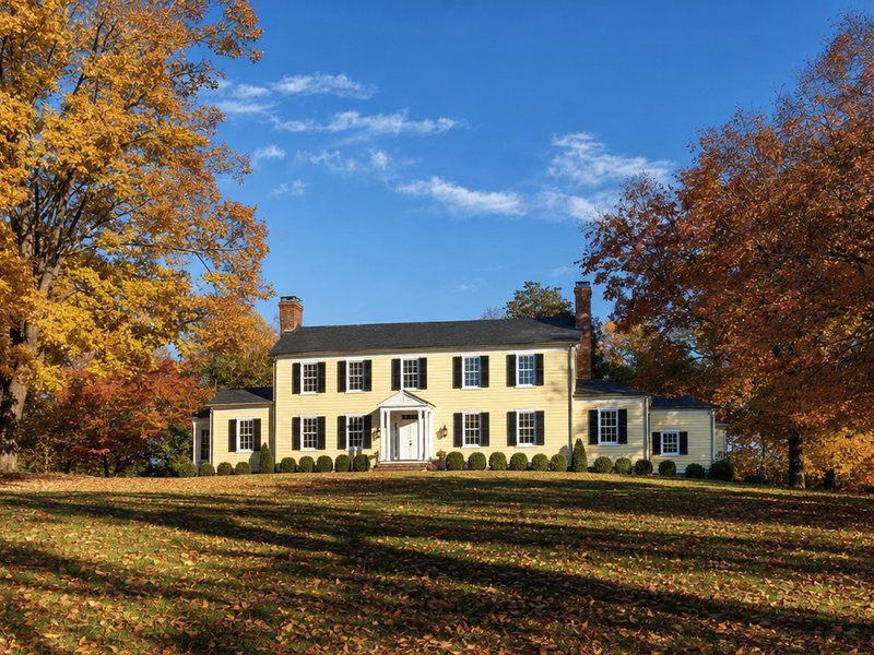 The cream Hunter House at Nottoway Park in fall, with a white columned entry and leaves on the lawn