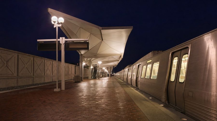 A Metro platform at night with a train beside the canopy